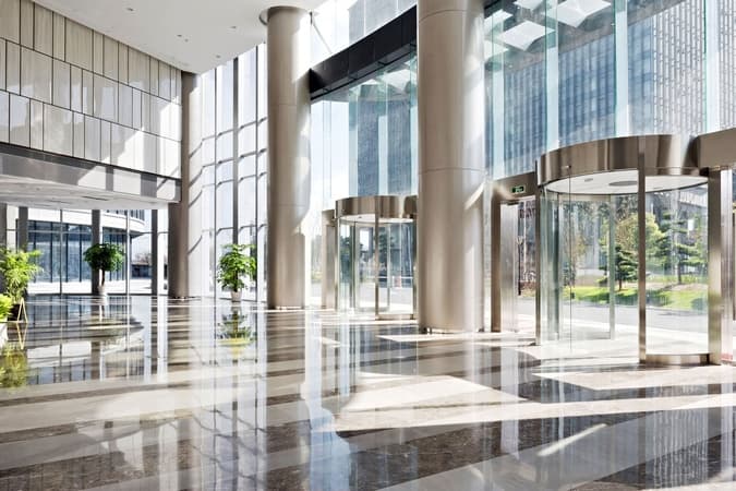 Modern commercial building lobby with glass walls and revolving door, representing secure and connected property management environments.