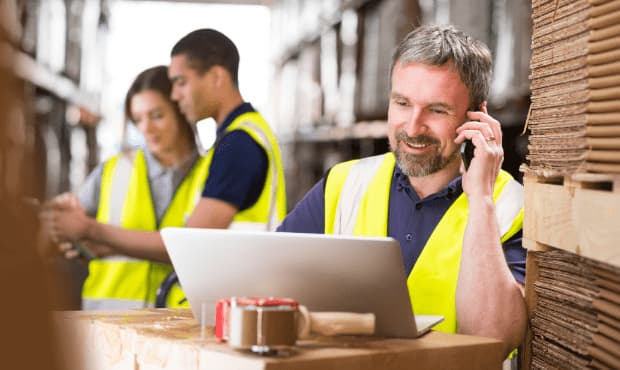 Warehouse employees using commercial cell signal boosters for reliable industrial cellular connectivity