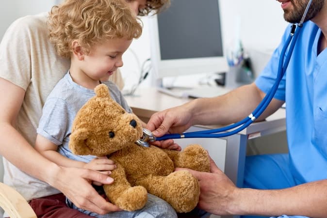Doctor checking a child’s teddy bear with a stethoscope, representing healthcare wireless solutions that support patient care and communication.